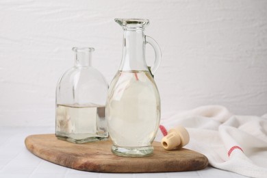 Photo of Vinegar in glass jug and bottle on white table