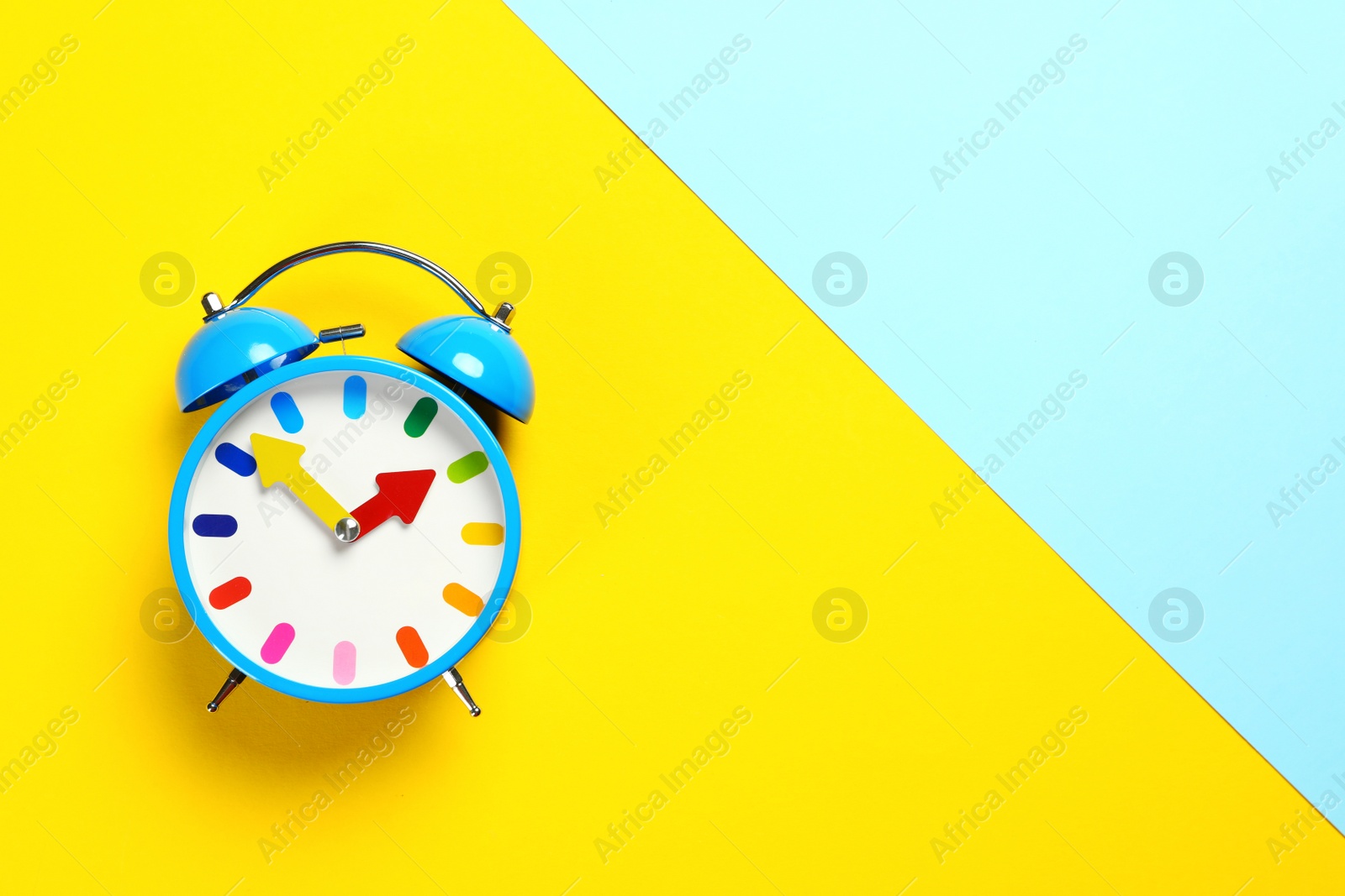 Photo of Top view of alarm clock on colorful background. Space for text