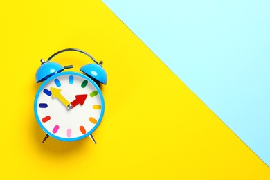Photo of Top view of alarm clock on colorful background. Space for text