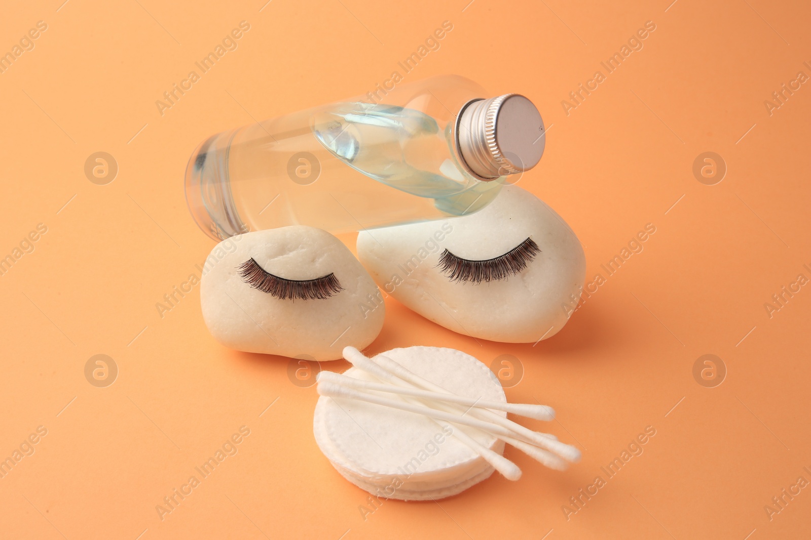Photo of Composition with makeup remover and false eyelashes on pale orange background