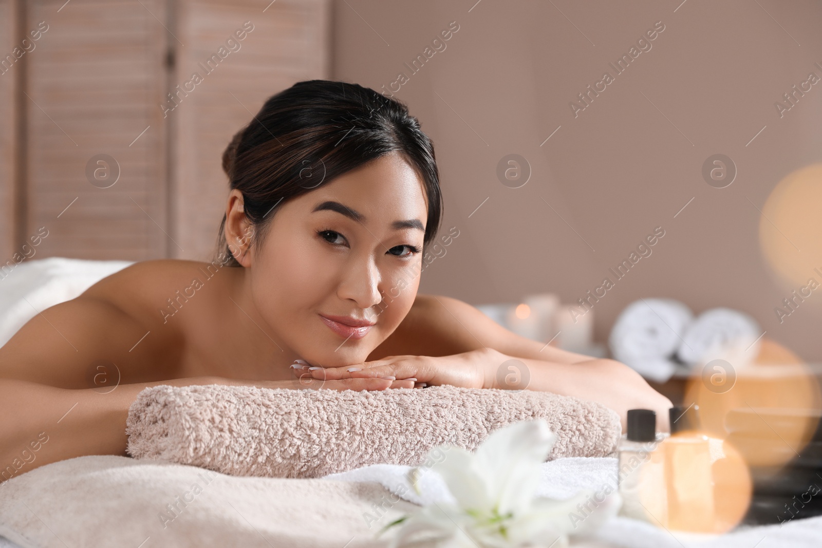 Photo of Beautiful Asian woman lying on massage table in spa salon. Space for text