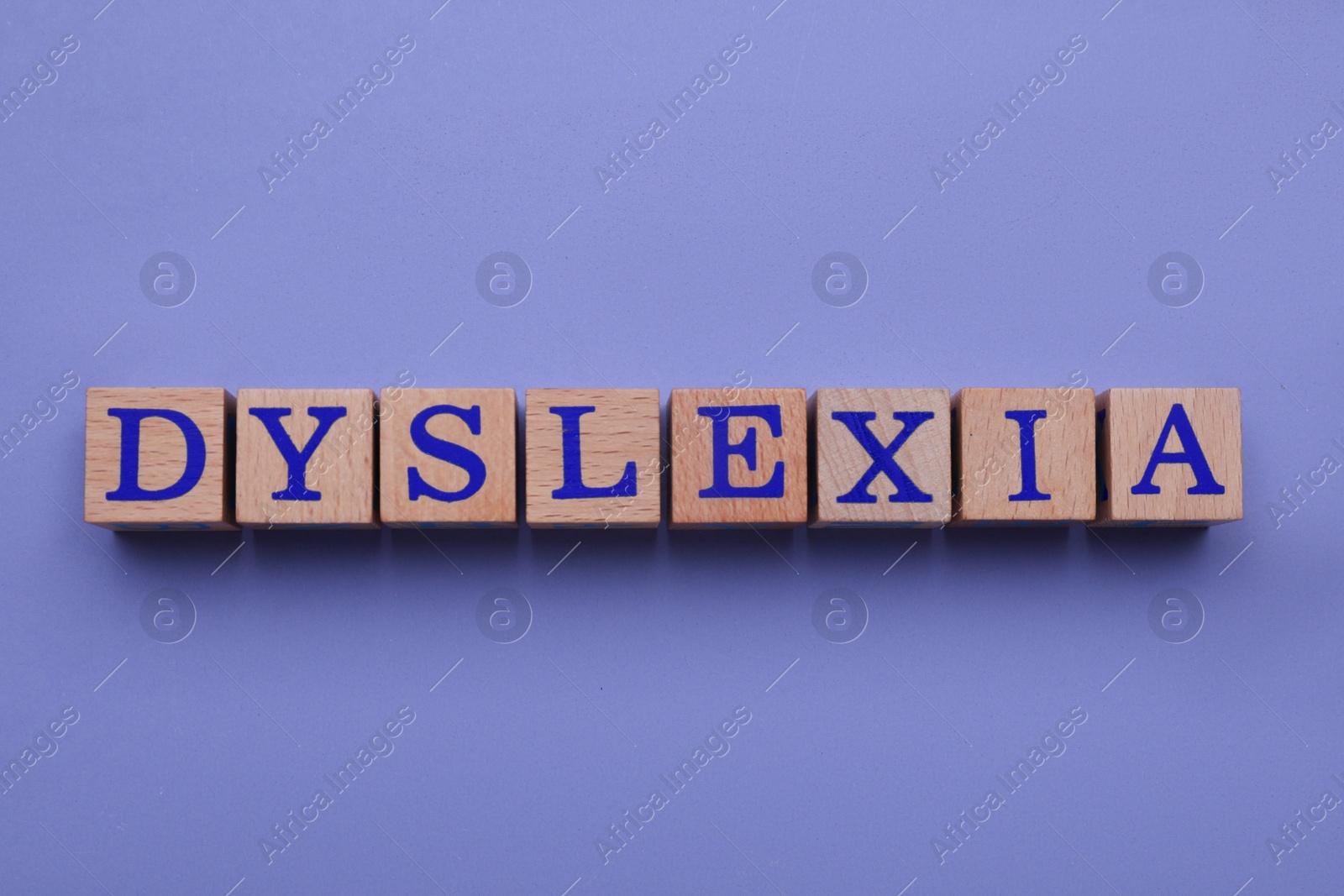 Photo of Wooden cubes with word Dyslexia on violet background, flat lay