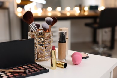 Different cosmetic products on white table in makeup room