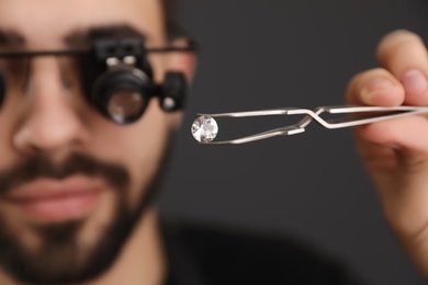 Photo of Male jeweler evaluating gemstone in workshop, closeup