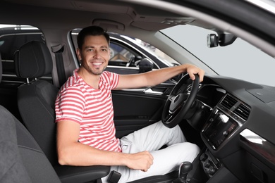 Happy man testing new car in salon