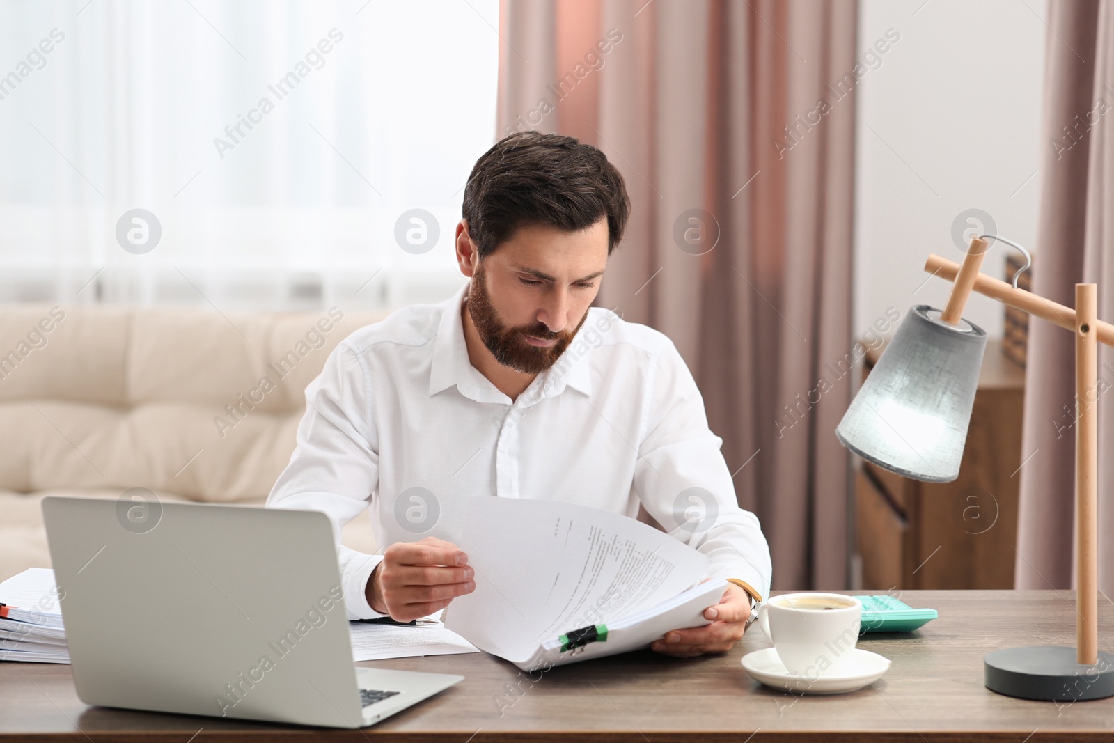 Photo of Businessman working with documents at wooden table in office