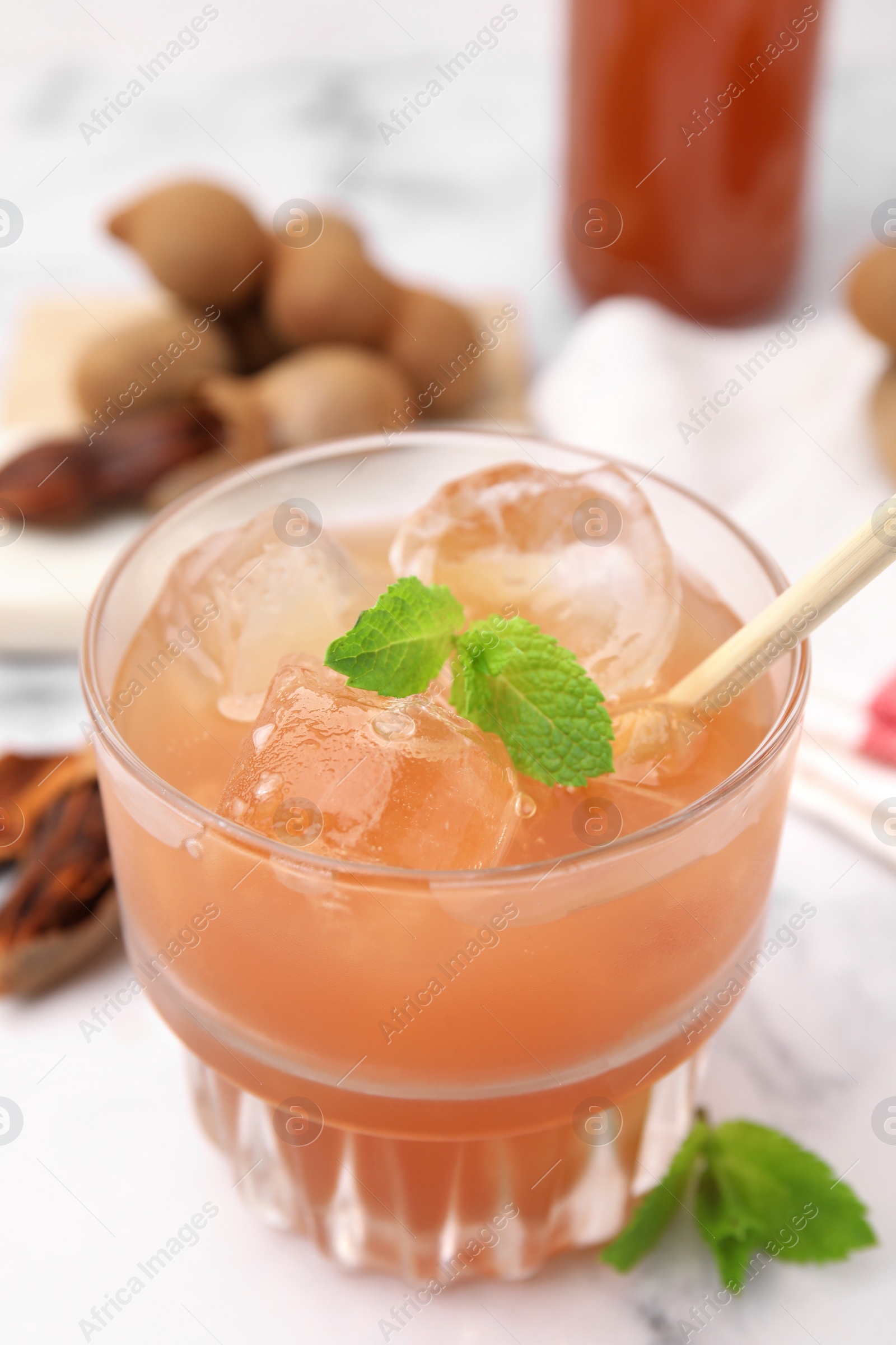 Photo of Freshly made tamarind juice with mint on white table, closeup. Space for text