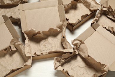 Photo of Many open cardboard boxes with crumpled paper on white wooden floor, above view