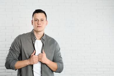 Photo of Handsome young man near white brick wall. Space for text