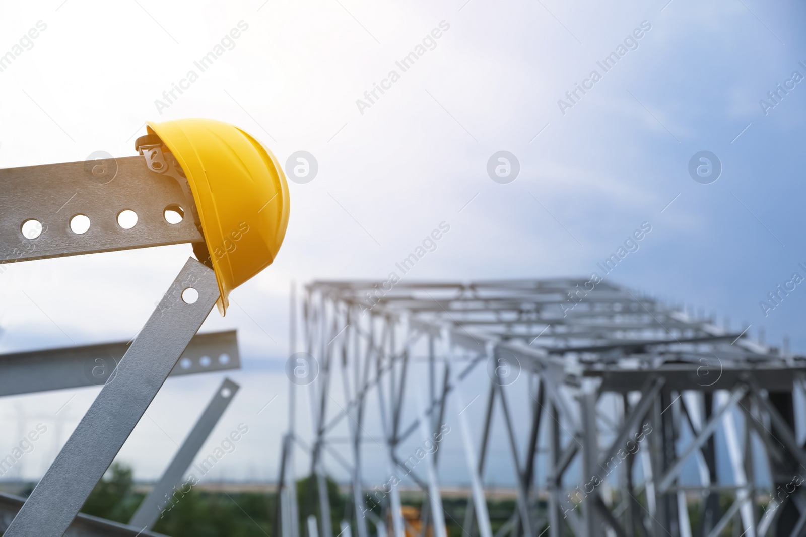 Photo of High voltage tower construction with yellow hard hat outdoors. Installation of electrical substation