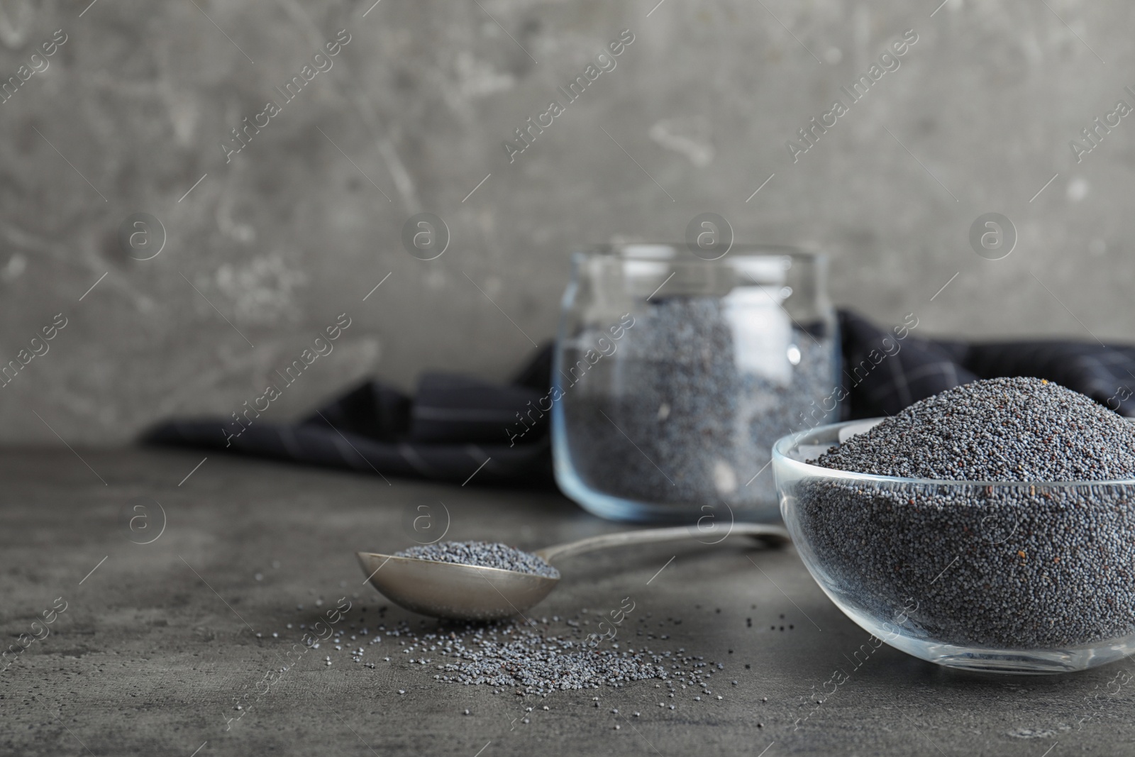 Photo of Poppy seeds in bowl and spoon on table. Space for text