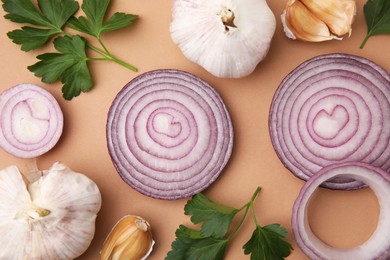 Fresh red onions, garlic and parsley on beige background, flat lay