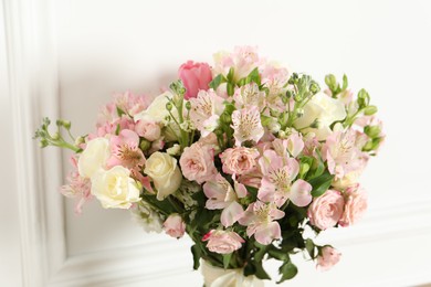 Beautiful bouquet of fresh flowers near white wall