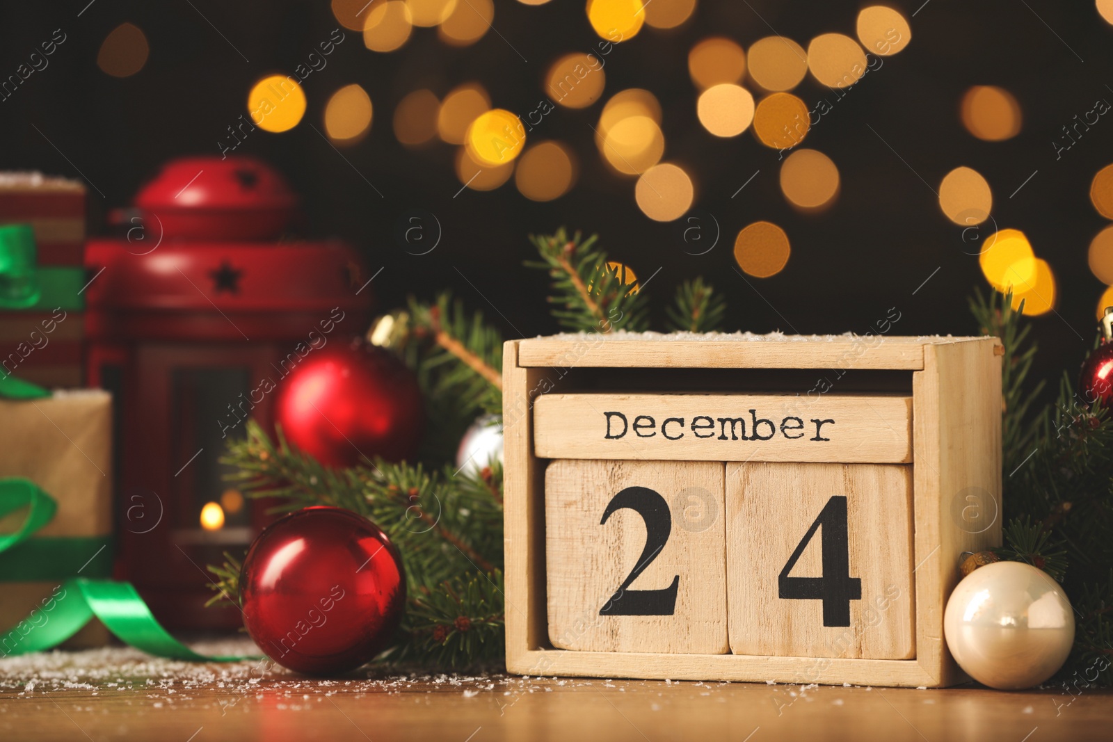 Photo of December 24 - Christmas Eve. Wooden block calendar and decor on table against blurred festive lights