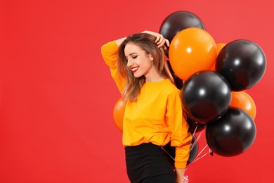 Photo of Beautiful woman with balloons on red background, space for text. Halloween party