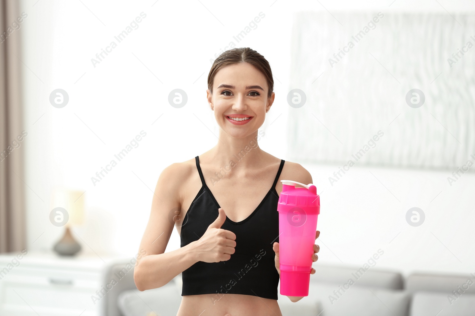 Photo of Athletic young woman with protein shake at home