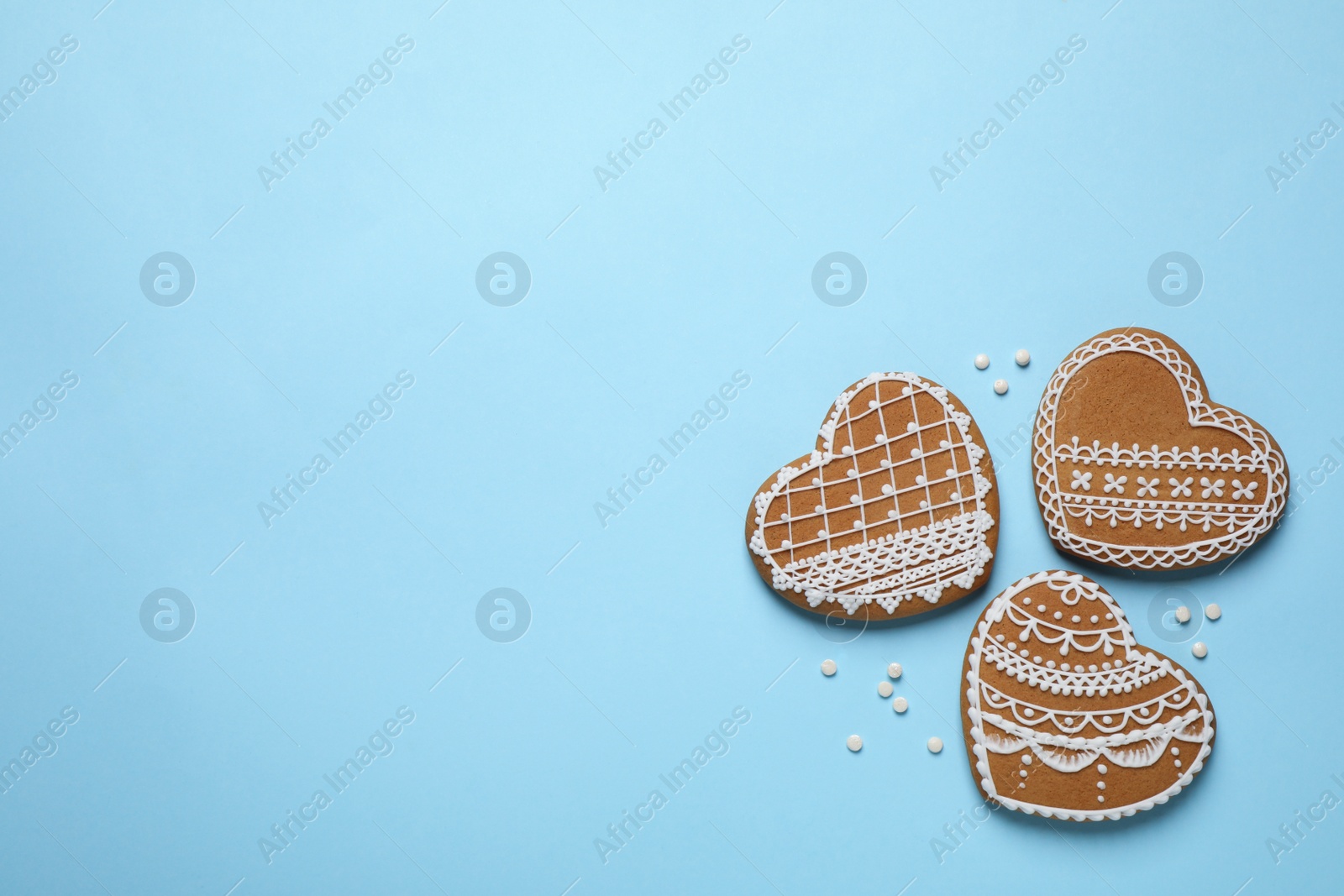 Photo of Tasty heart shaped gingerbread cookies on light blue background, flat lay. Space for text