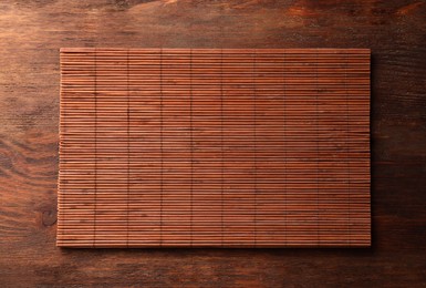 Photo of Bamboo mat on wooden table, top view. Space for text