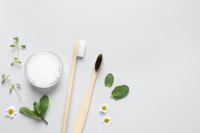 Photo of Bamboo toothbrushes, beautiful chamomile flowers, sea salt and herbs on white background, flat lay. Space for text