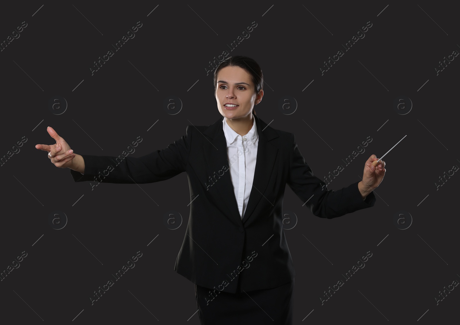 Photo of Happy young conductor with baton on dark background