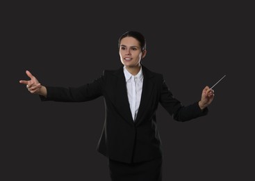 Photo of Happy young conductor with baton on dark background