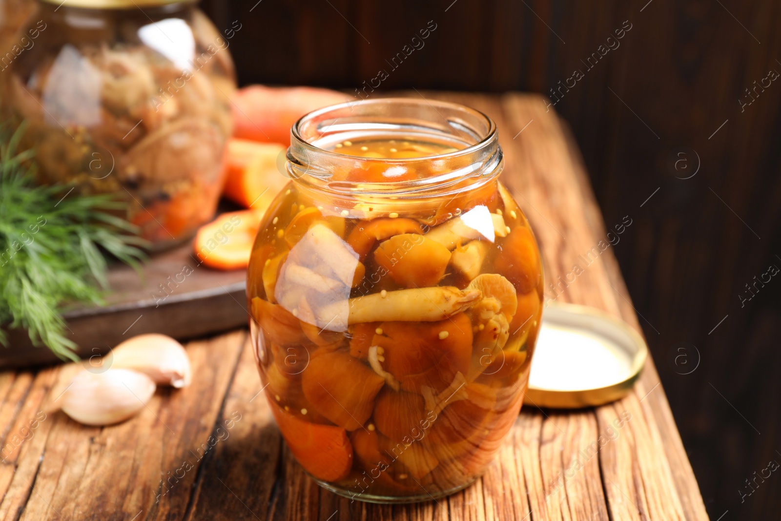 Photo of Delicious marinated mushrooms in glass jar on wooden table