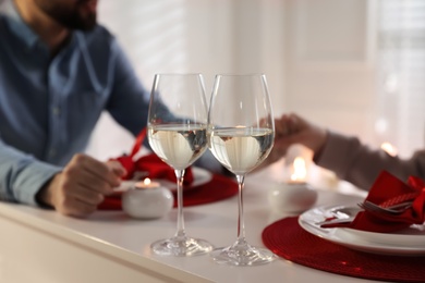 Photo of Couple having romantic dinner at home, focus on glasses of wine