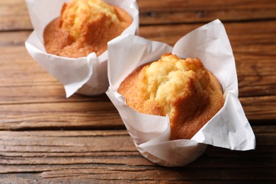 Photo of Delicious sweet muffins on wooden table, closeup. Space for text