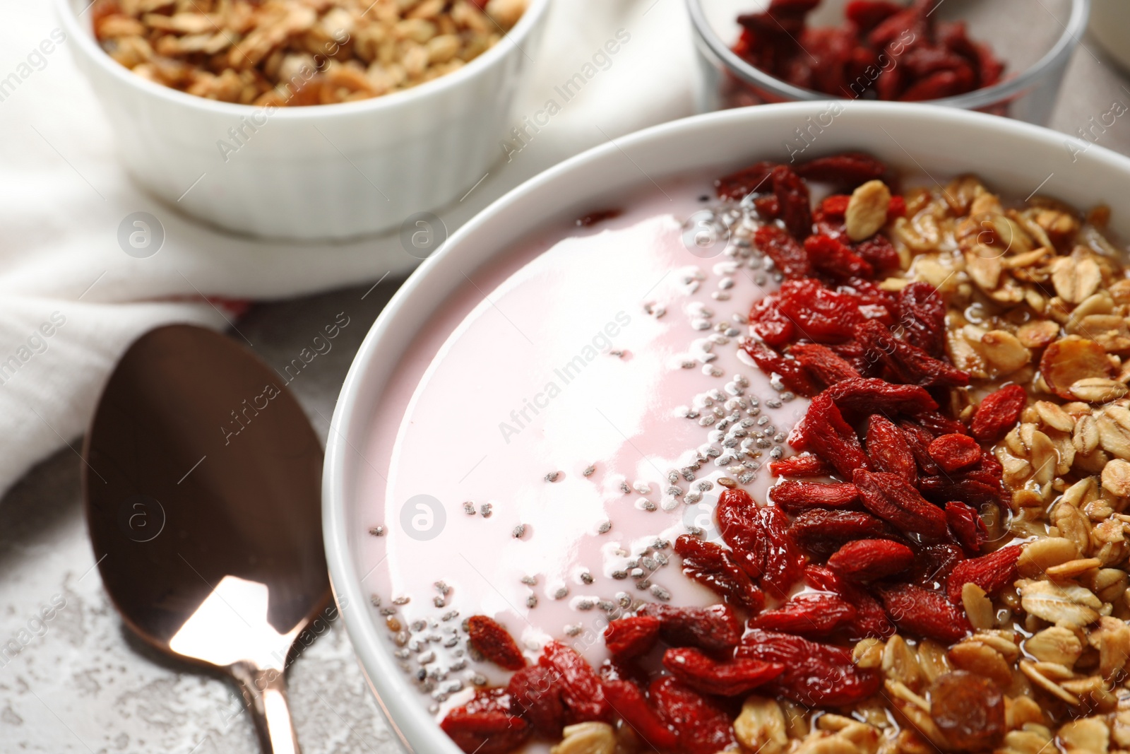 Photo of Smoothie bowl with goji berries and spoon on beige marble table, closeup