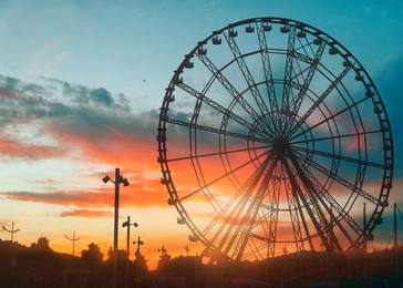 Image of Beautiful large Ferris wheel outdoors at sunset