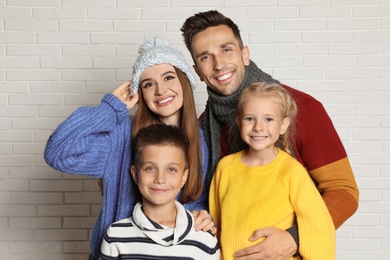 Happy family in warm clothes near white brick wall. Winter season