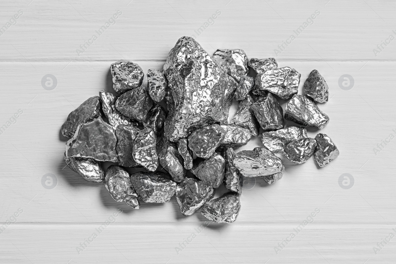 Photo of Pile of silver nuggets on white wooden table, top view