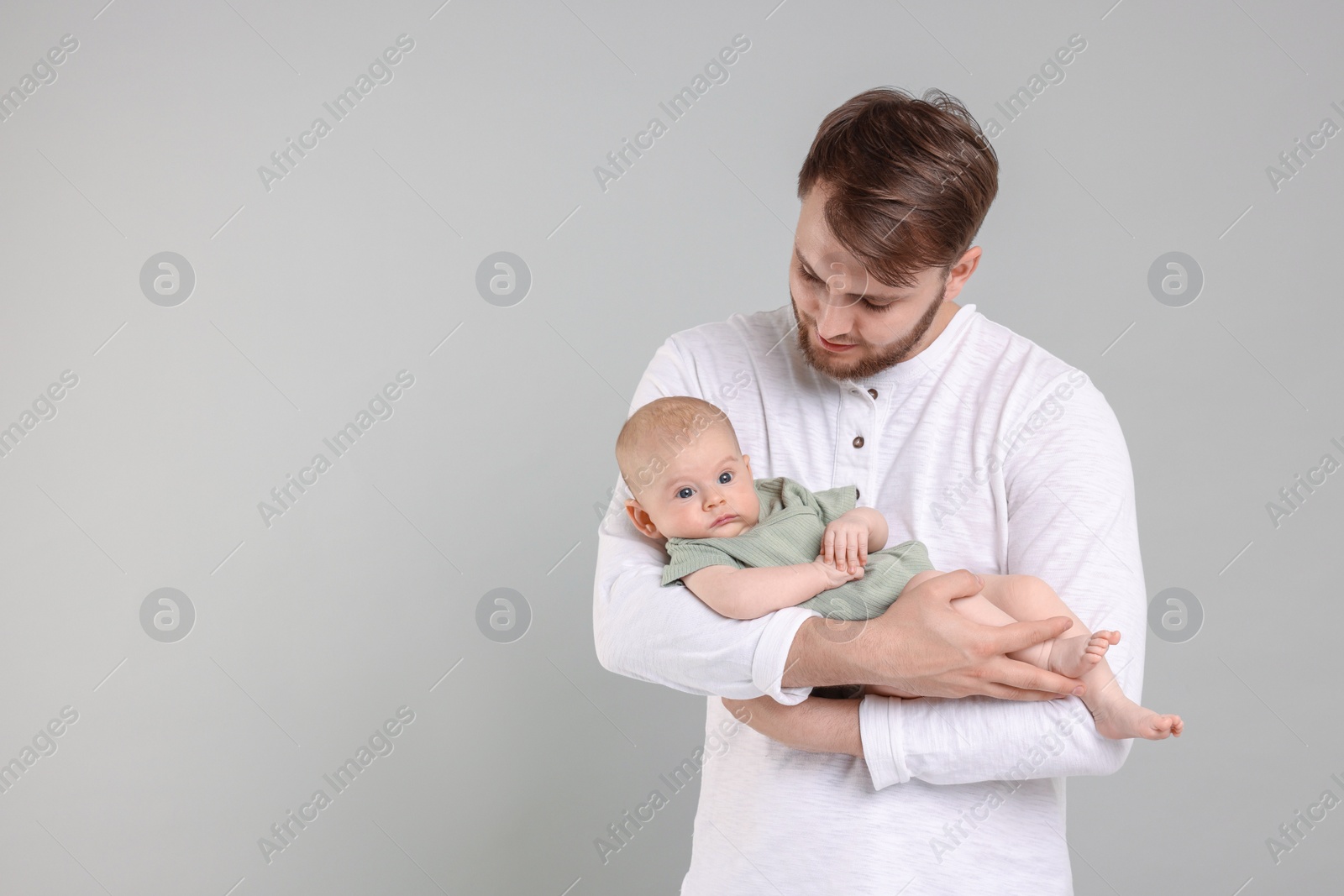 Photo of Father with his cute baby on grey background, space for text