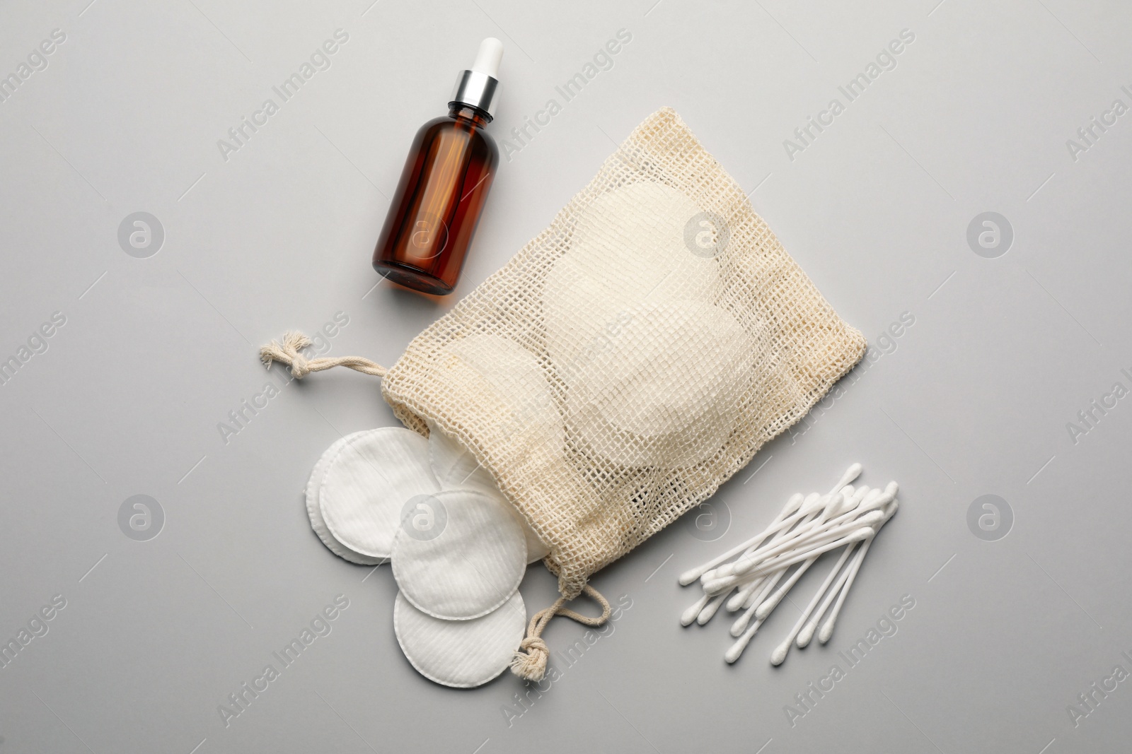 Photo of Cotton pads, swabs and makeup removal product on light grey background, flat lay