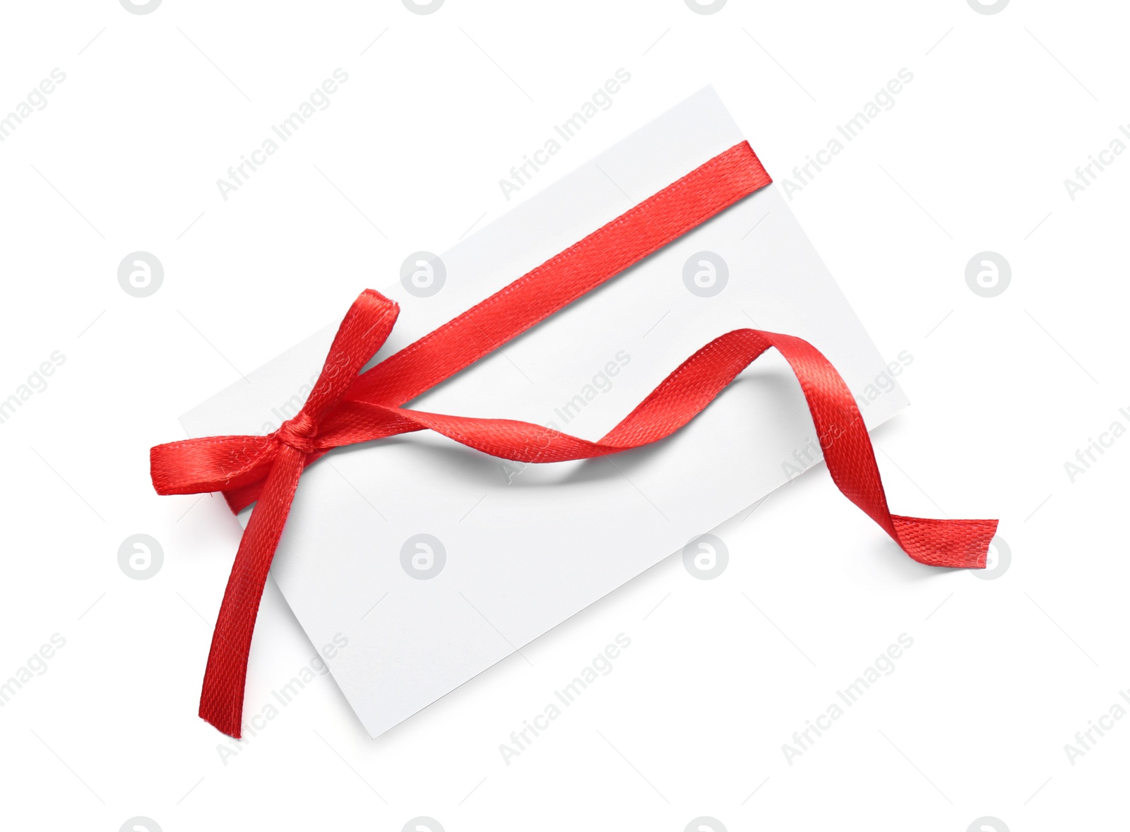 Photo of Blank gift tag with red satin ribbon on white background, top view