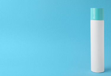 Photo of Bottle of dry shampoo on turquoise background. Space for text