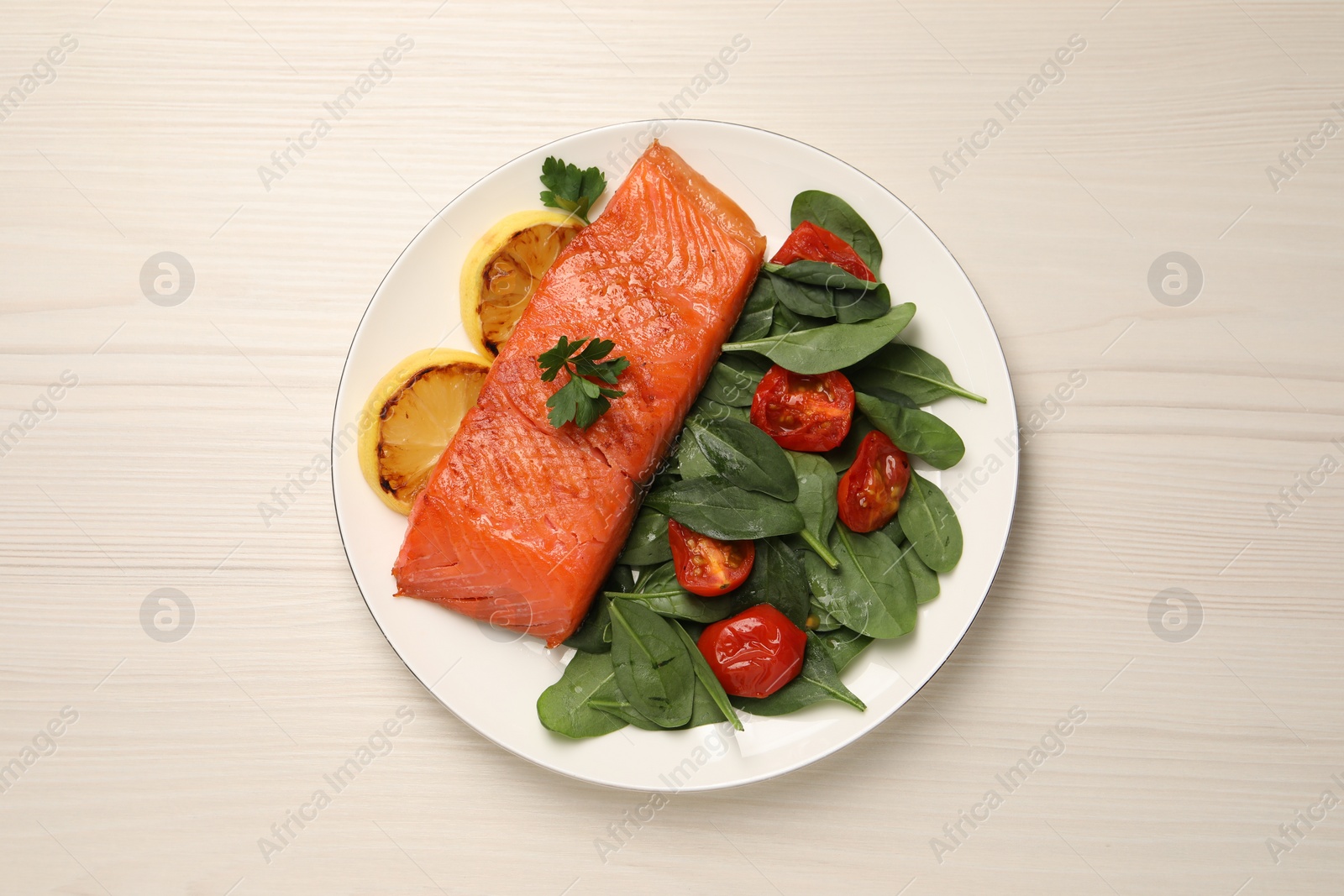 Photo of Tasty grilled salmon with basil, tomatoes and lemon on white wooden table, top view