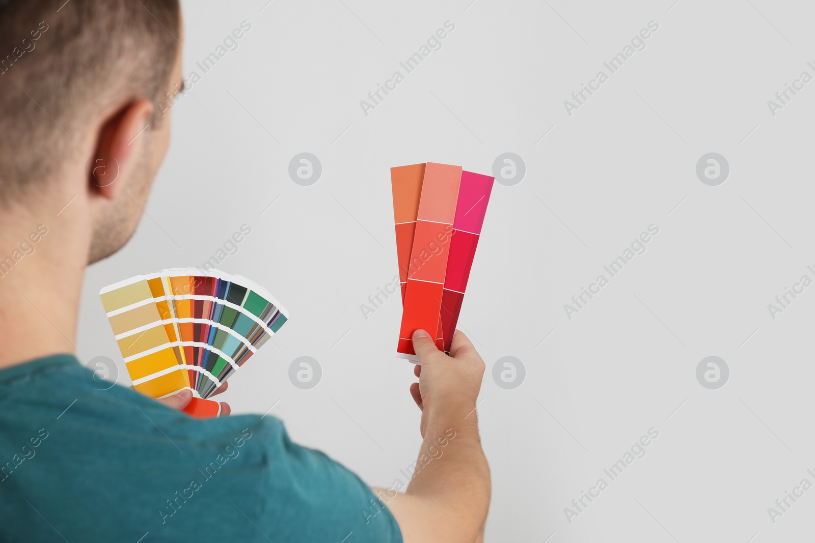 Photo of Man with palette choosing color for painting wall indoors, closeup. Interior design