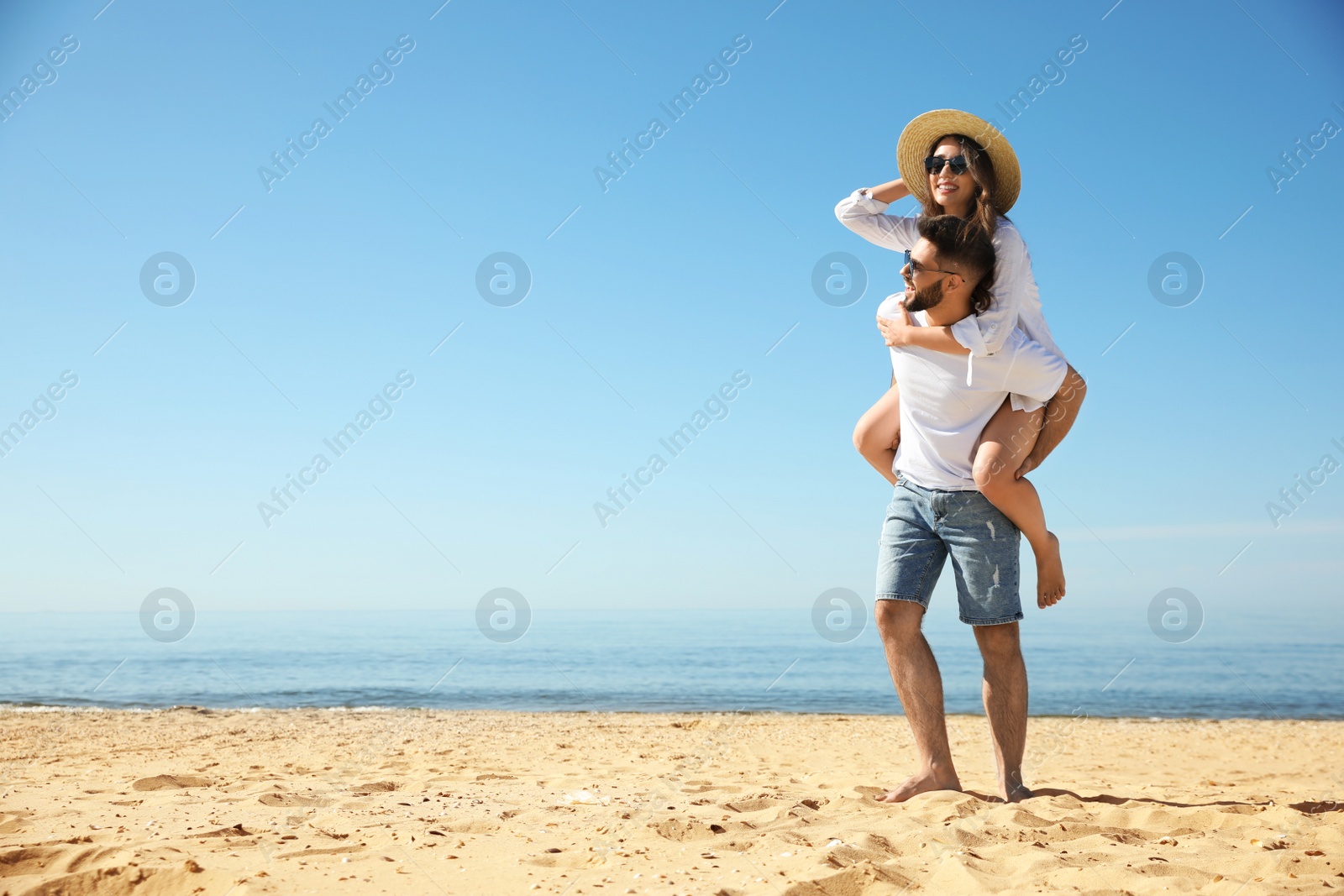 Photo of Happy young couple having fun on beach near sea. Honeymoon trip