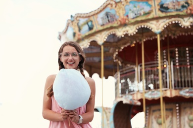 Photo of Young woman with cotton candy in amusement park. Space for text
