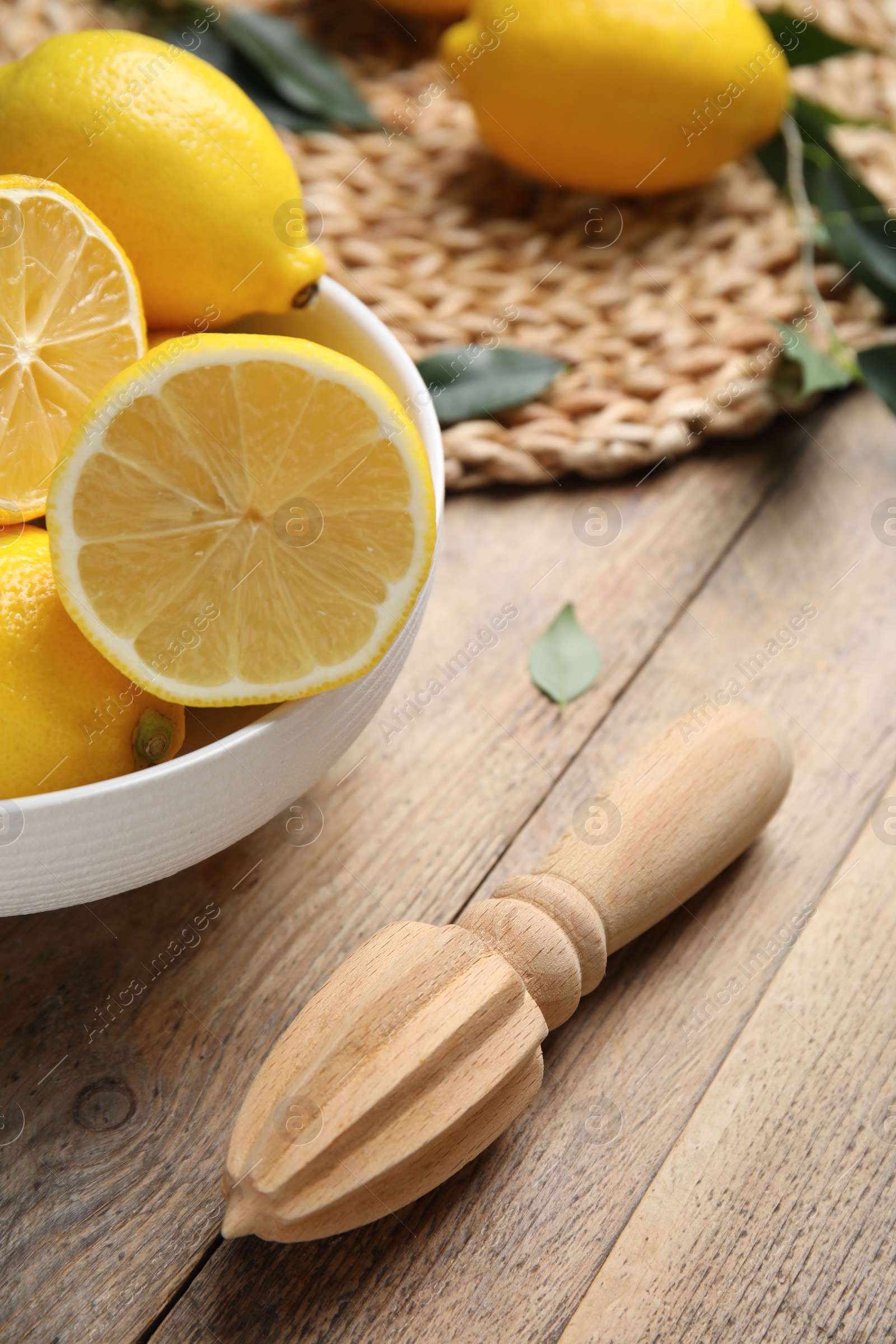 Photo of Squeezer with lemons on wooden table, closeup