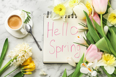 Photo of Notebook with words HELLO SPRING, cup of coffee and fresh flowers on white marble table, flat lay