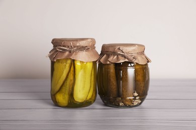 Photo of Jars with pickled cucumbers on white wooden table