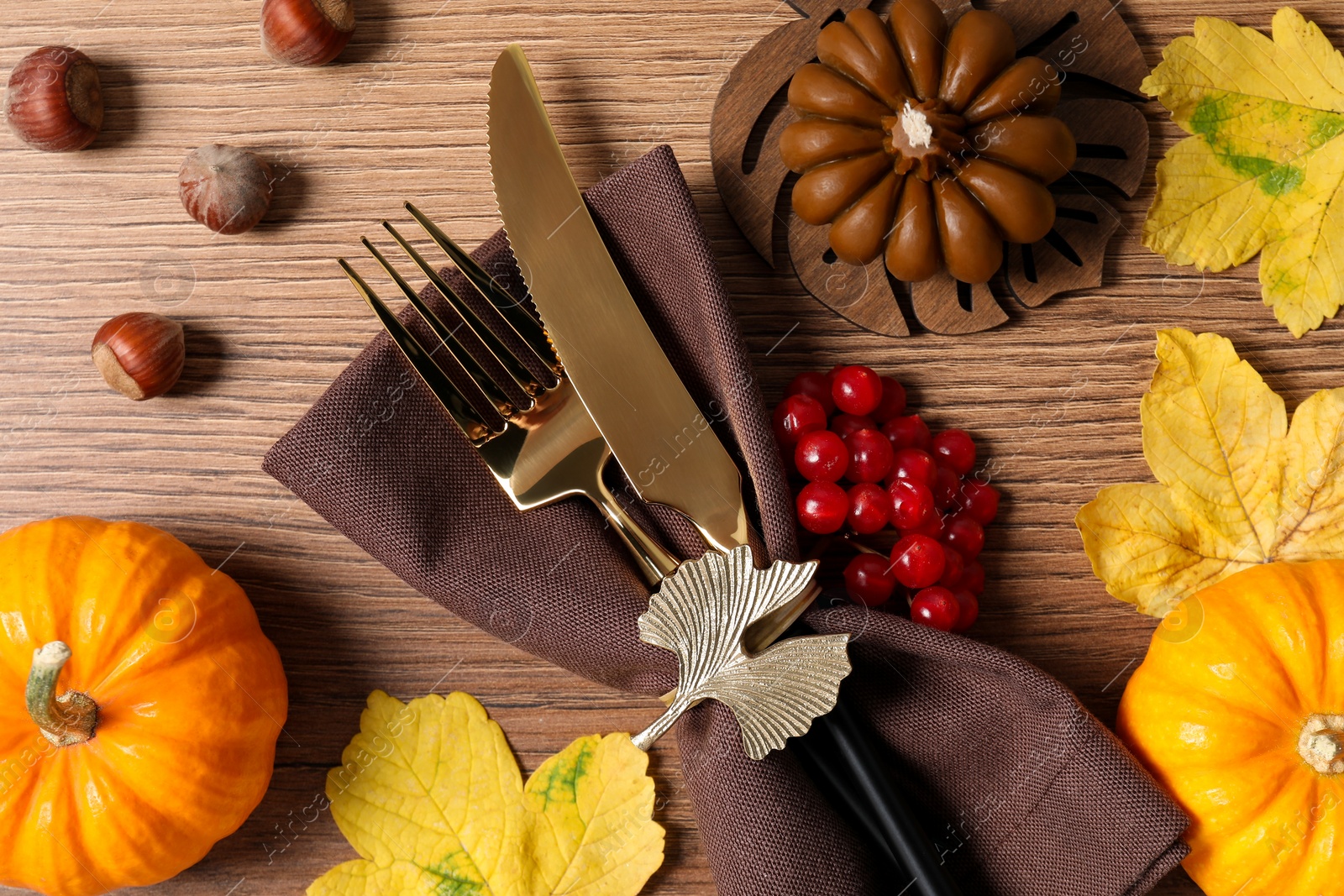 Photo of Thanksgiving table setting. Cutlery, napkin and autumn decor, flat lay