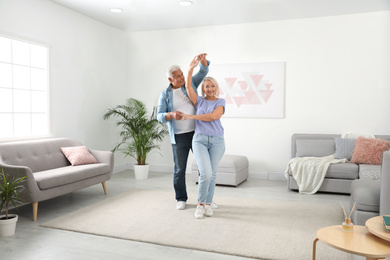 Photo of Happy mature couple dancing together in living room