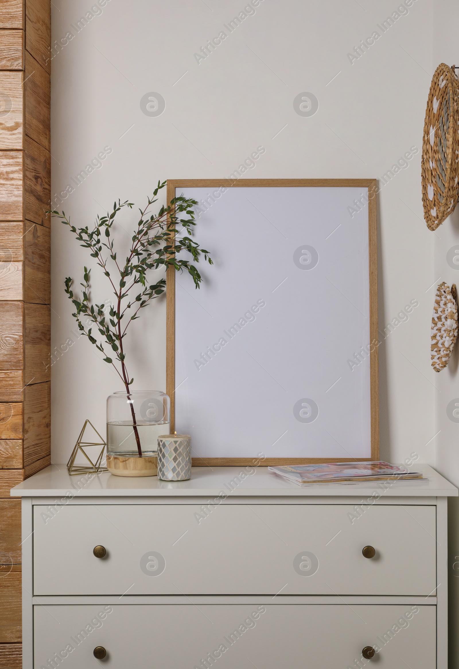 Photo of Blank frame on chest of drawers and decor indoors. Space for design