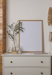 Blank frame on chest of drawers and decor indoors. Space for design