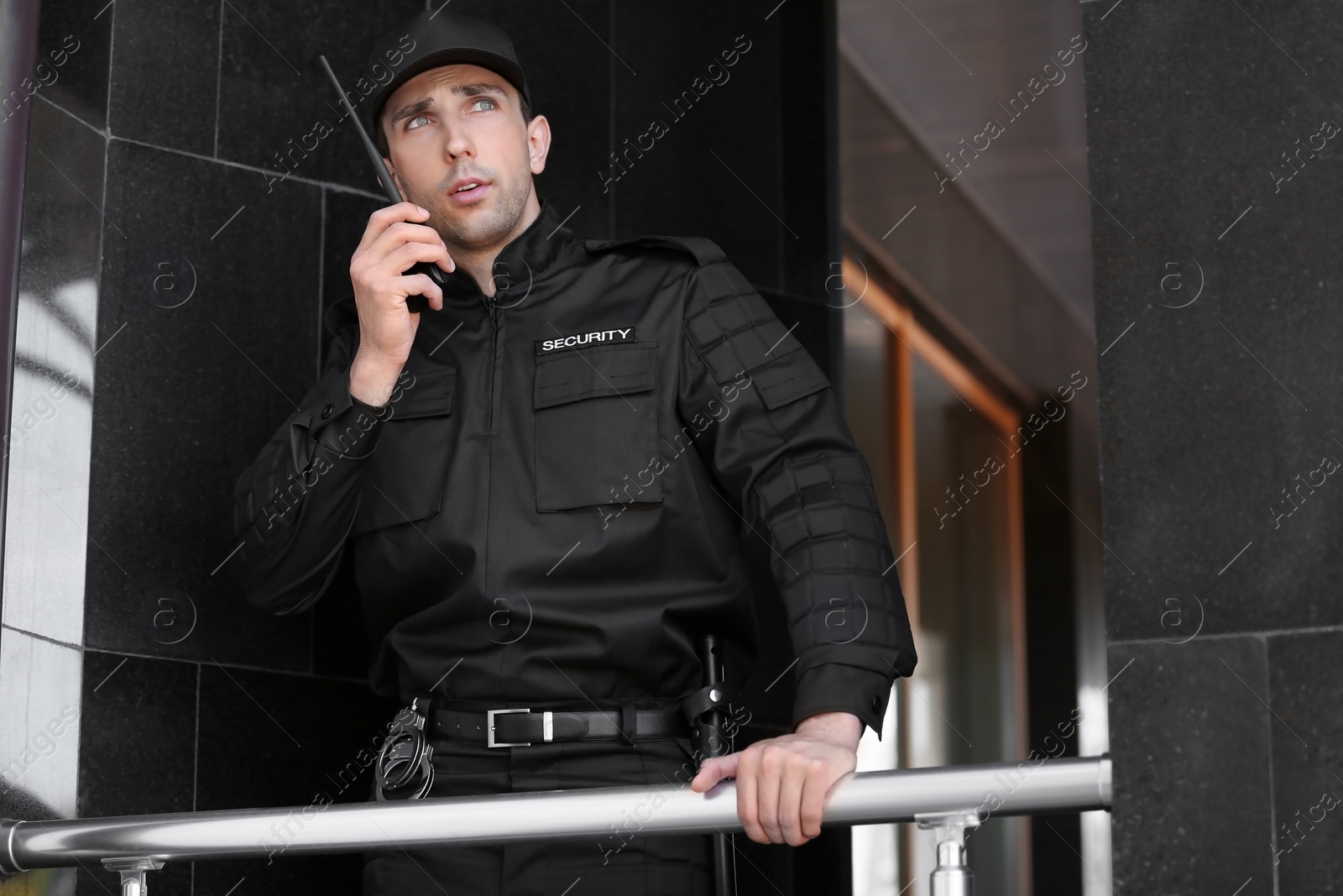 Photo of Male security guard using portable radio transmitter outdoors