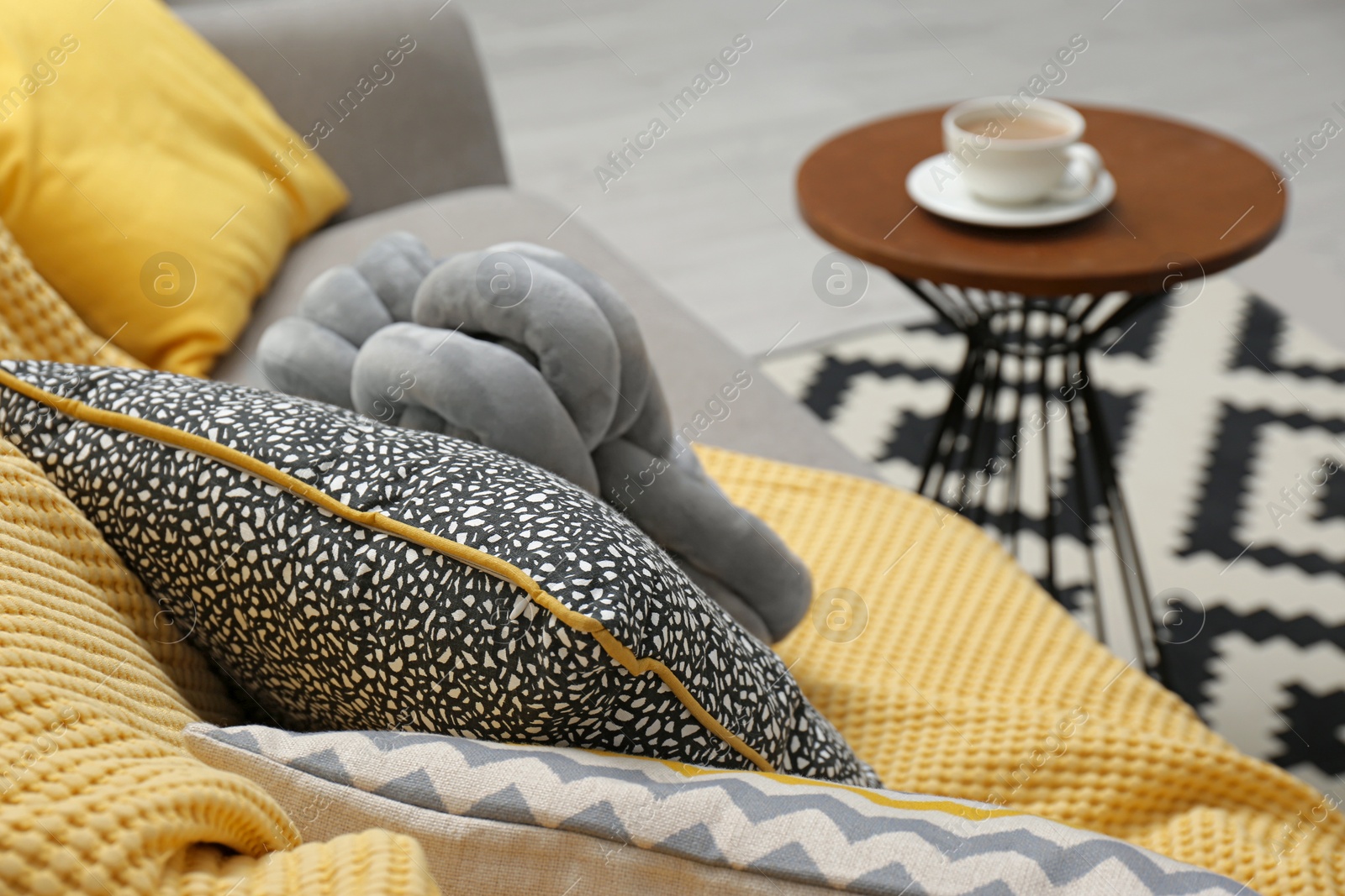 Photo of Soft pillows and yellow plaid on sofa in living room