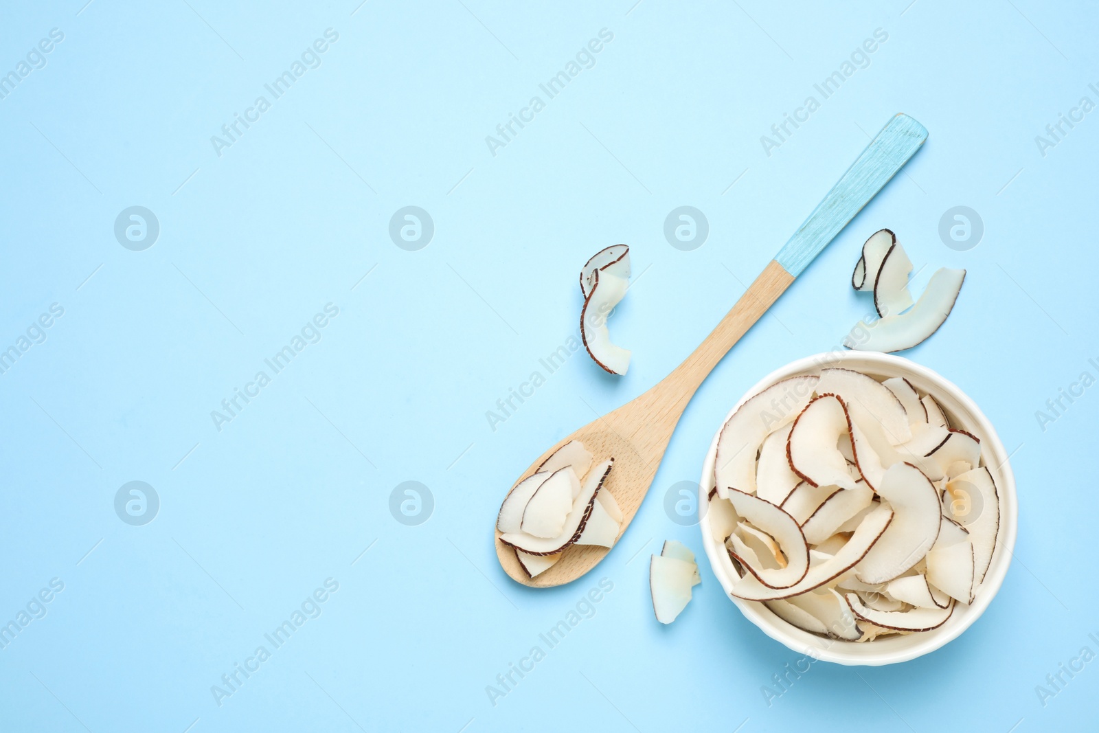 Photo of Flat lay composition with tasty coconut chips on light blue background. Space for text